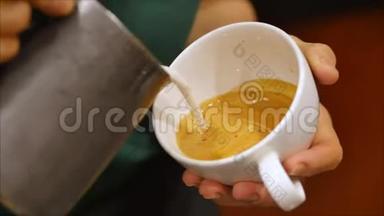 专业咖啡师。 制作新鲜的磨碎咖啡，咖啡师制作拉丁艺术，将牛奶倒入杯子，同时制作